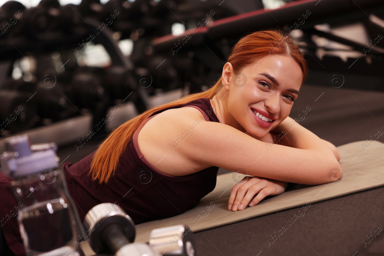 Photo of Happy young woman lying on mat in gym