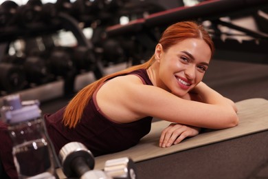 Happy young woman lying on mat in gym