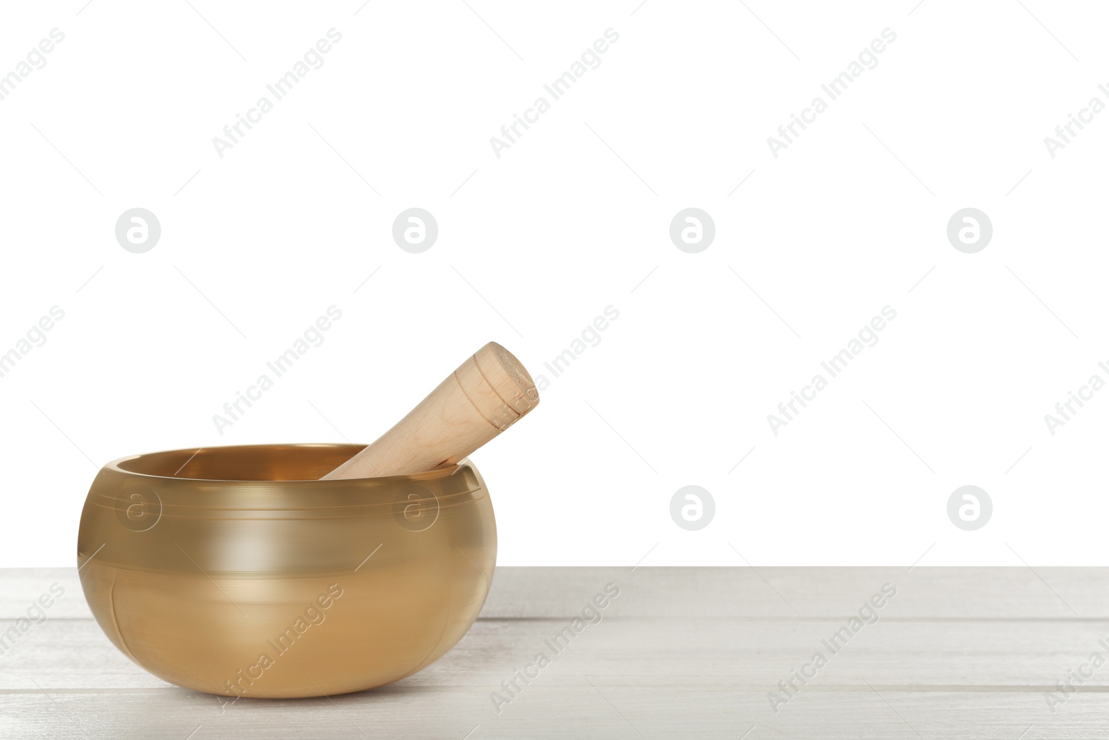 Photo of Golden singing bowl and mallet on wooden table against white background, space for text