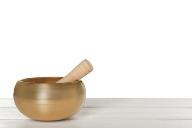 Photo of Golden singing bowl and mallet on wooden table against white background, space for text