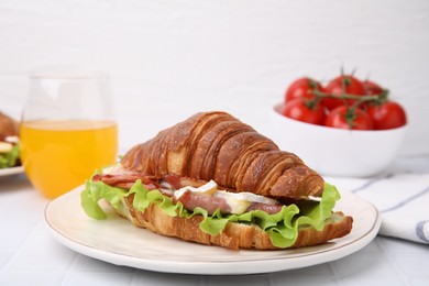 Photo of Tasty croissant with brie cheese, ham and bacon on white table, closeup