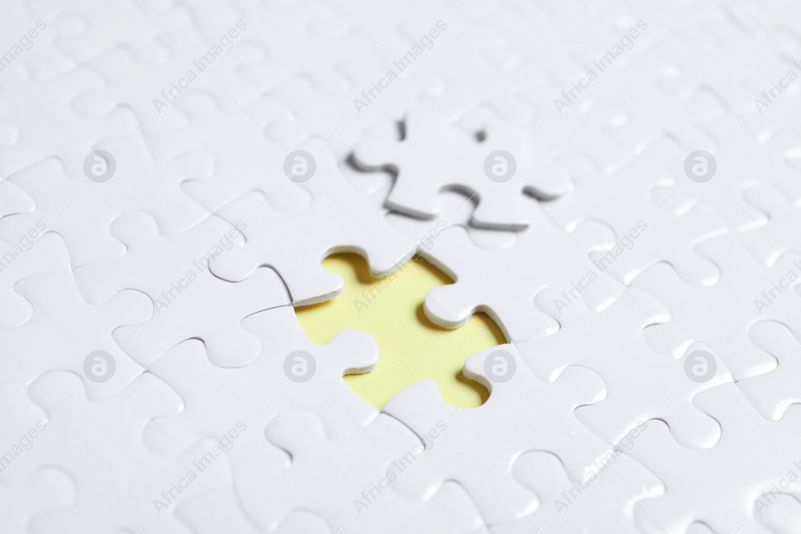 Photo of Blank white puzzle with separated piece on yellow background