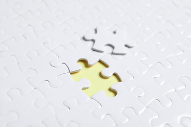 Blank white puzzle with separated piece on yellow background