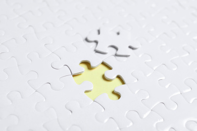 Photo of Blank white puzzle with separated piece on yellow background