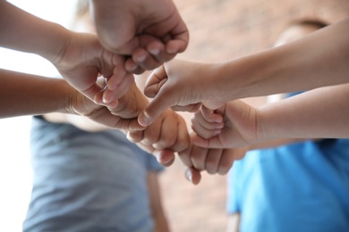 Photo of Little children putting their hands together on blurred background. Unity concept