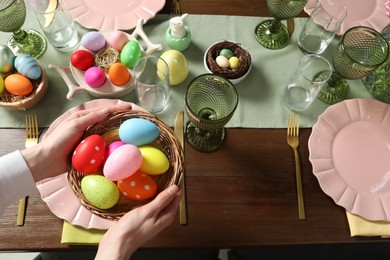 Woman setting table for festive Easter dinner at home, above view