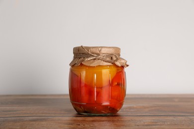 Jar with pickled bell peppers on wooden table