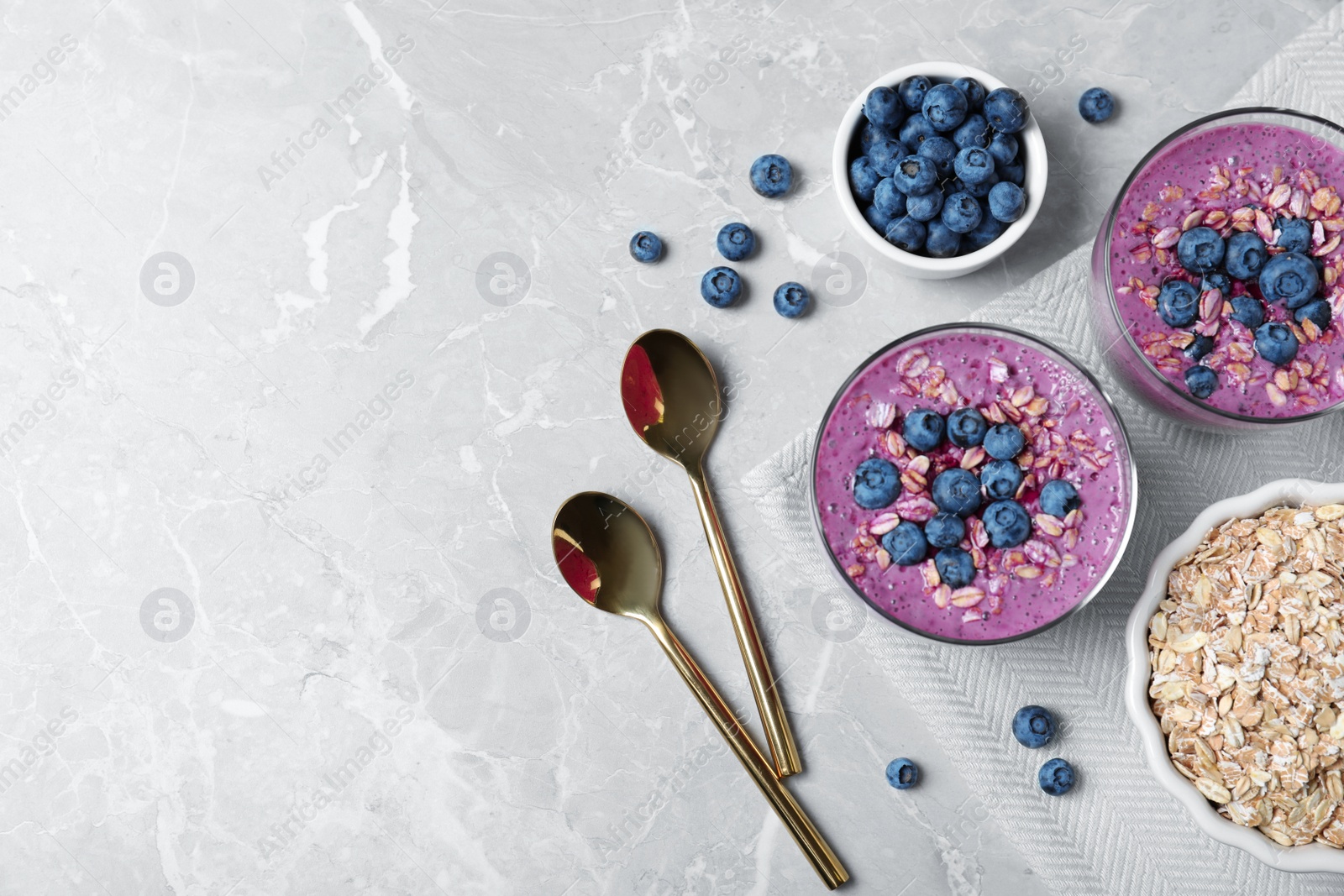 Photo of Tasty blueberry smoothie served on grey table, flat lay. Space for text