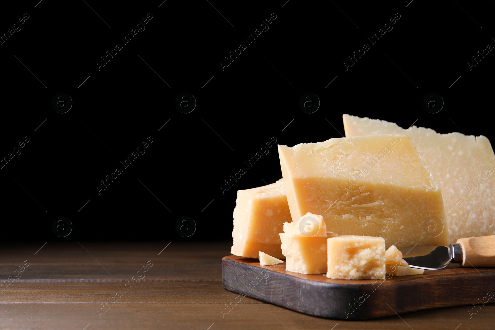 Photo of Delicious parmesan cheese with knife on wooden table. Space for text