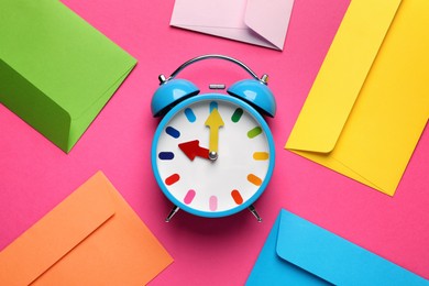 Alarm clock and bright envelopes on pink background, flat lay. Reminder concept