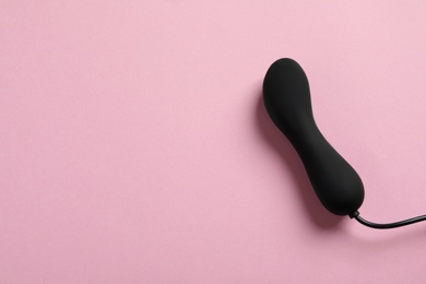 Photo of Black vibrator on pink background, top view with space for text. Sex toy