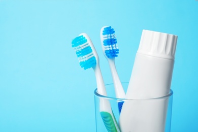 Photo of Glass with brushes and toothpaste on color background. Space for text