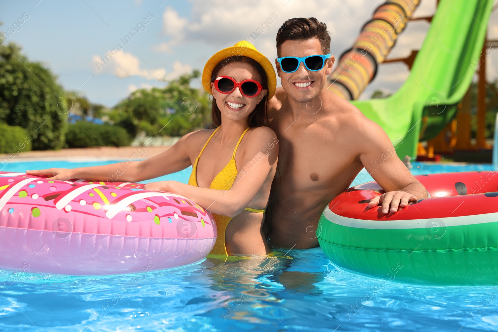 Photo of Happy couple with inflatable rings in swimming pool. Summer vacation