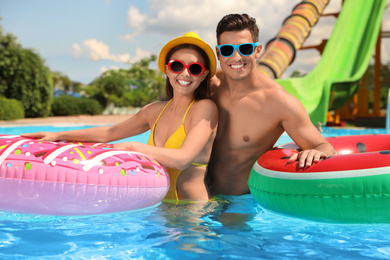 Happy couple with inflatable rings in swimming pool. Summer vacation