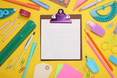 Photo of Flat lay composition of clipboard with notes and other school stationery on yellow background, space for text. Back to school