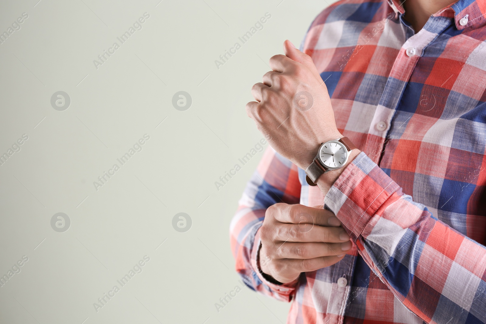 Photo of Young man with wristwatch on grey background. Time concept