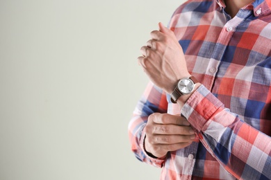 Young man with wristwatch on grey background. Time concept