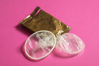 Photo of Unrolled female condom and torn package on pink background, closeup. Safe sex