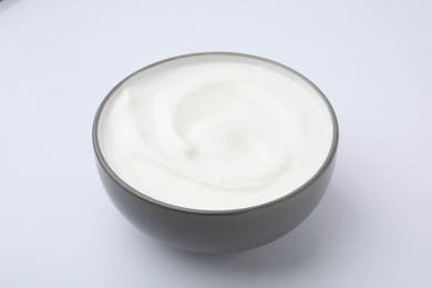 Photo of Delicious natural yogurt in bowl on white background