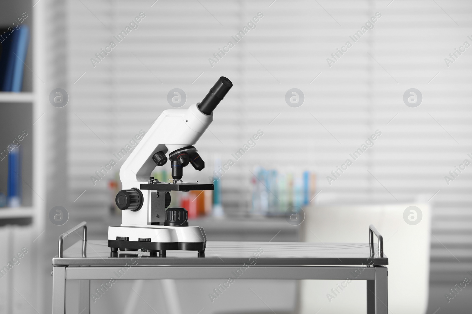 Photo of Modern medical microscope on metal table in laboratory, space for text