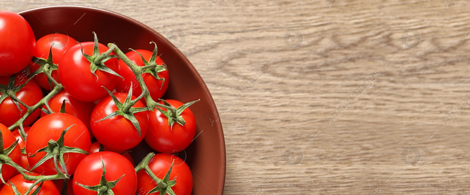 Image of Top view of plate with fresh tomatoes on wooden table, space for text. Banner design 