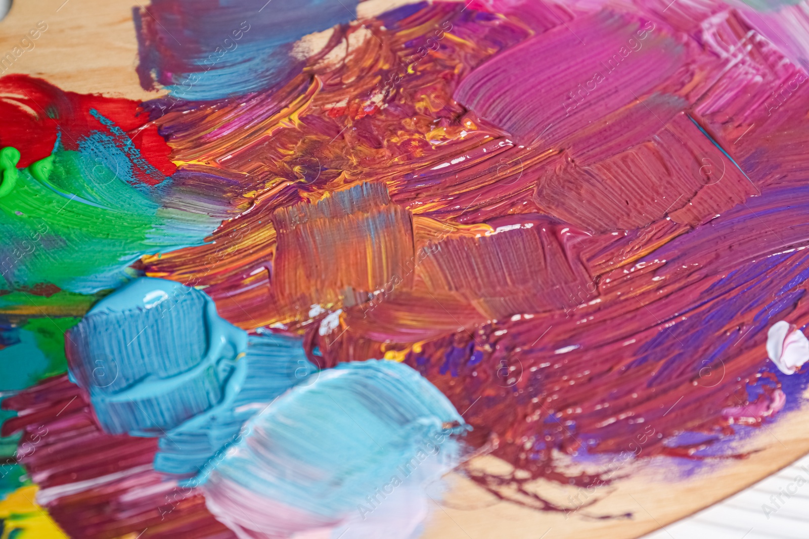 Photo of Wooden artist's palette with colorful paints, closeup
