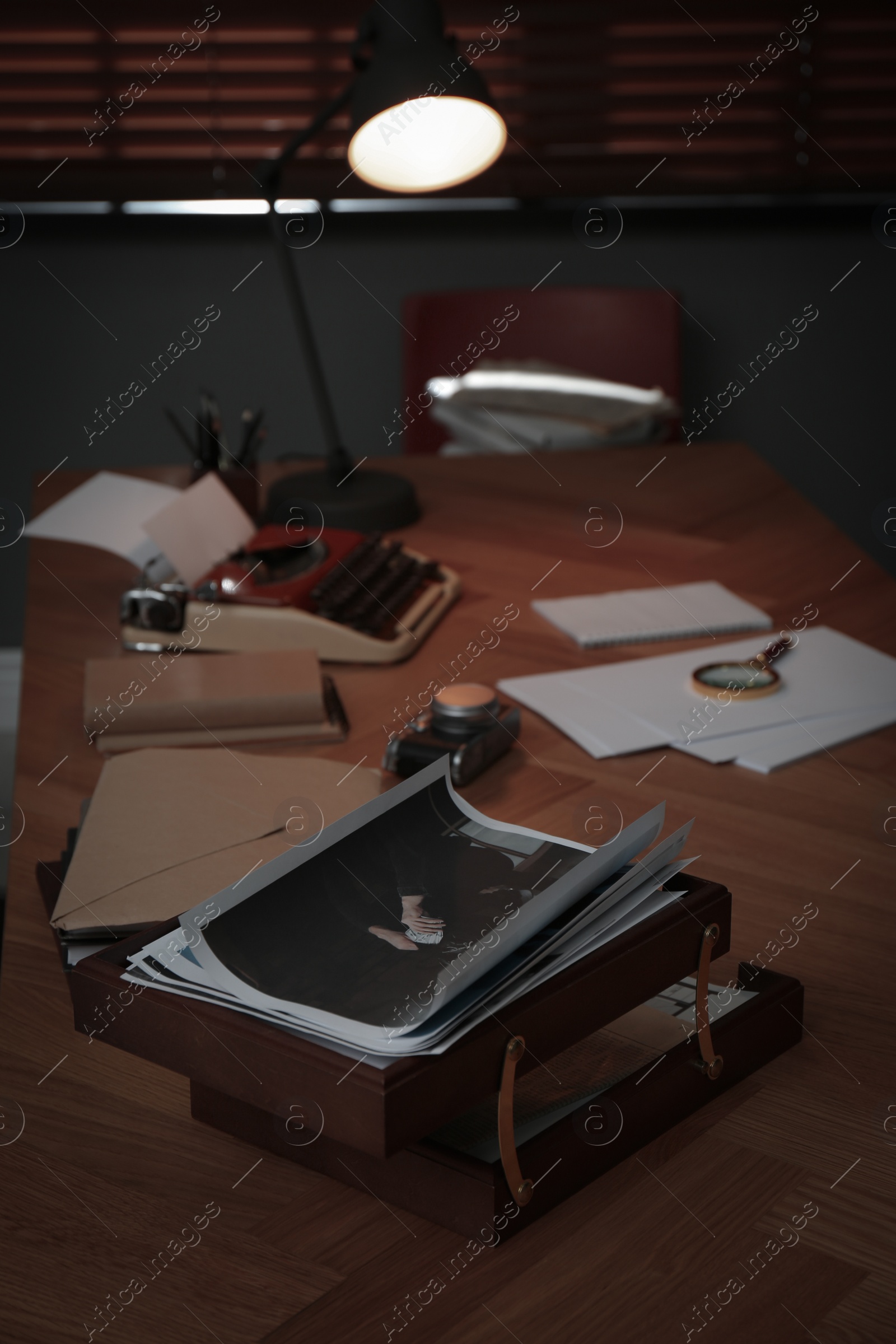 Photo of Photos, papers and typewriter on desk in office. Detective's workplace