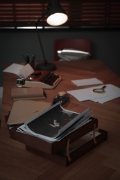 Photos, papers and typewriter on desk in office. Detective's workplace