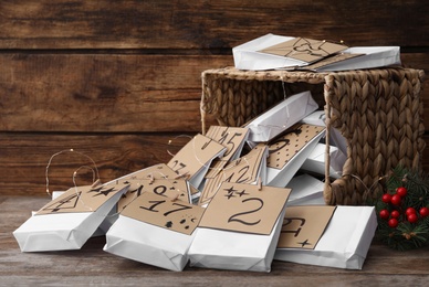 Photo of Paper bags, fir branches and garland on wooden table. Christmas advent calendar