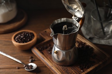 Photo of Brewed coffee in moka pot and beans on wooden table