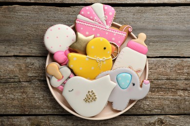 Cute tasty cookies of different shapes on wooden table, top view. Baby shower party