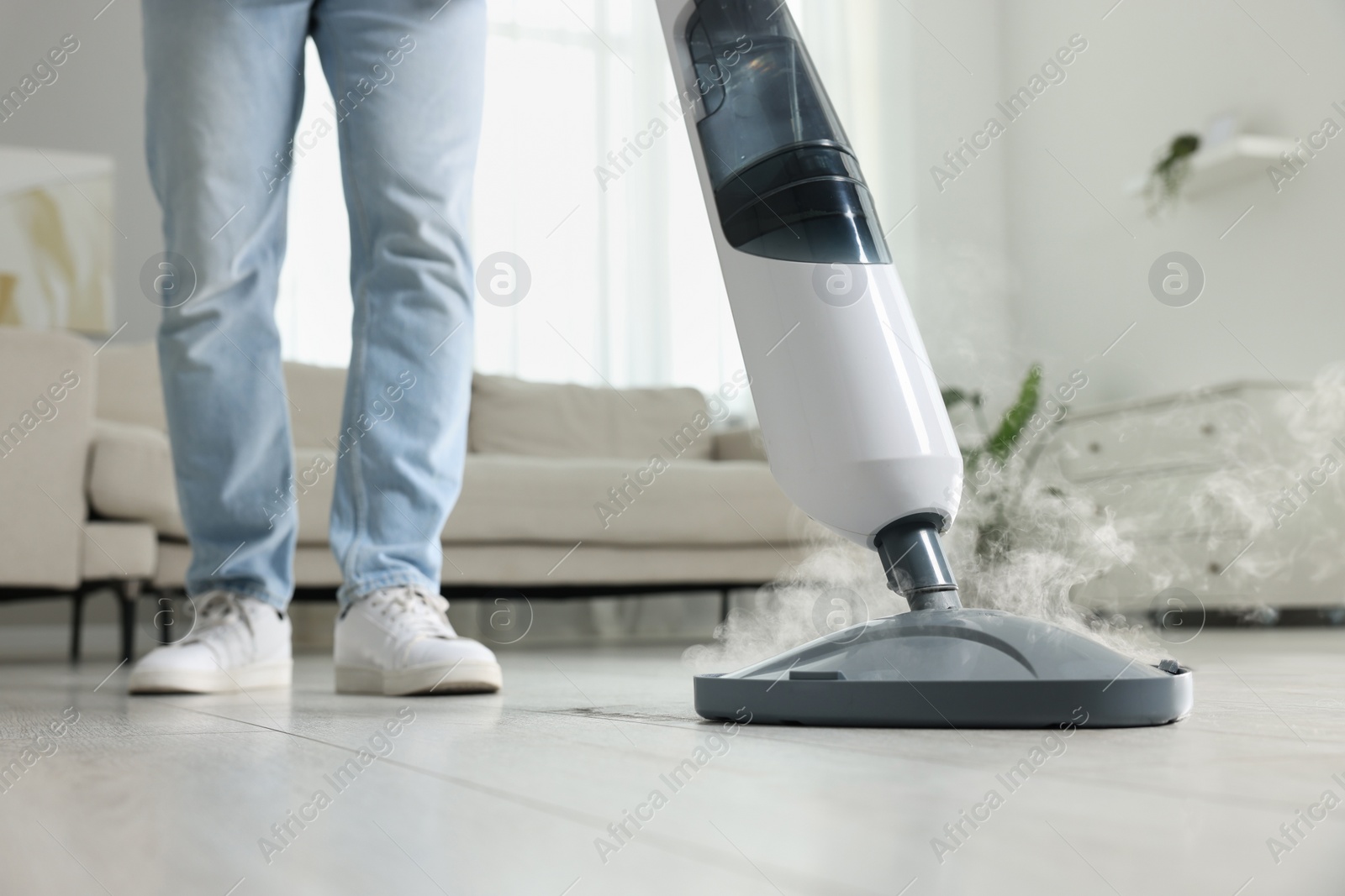 Photo of Man cleaning floor with steam mop at home, closeup