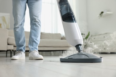 Man cleaning floor with steam mop at home, closeup