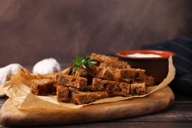 Crispy rusks with rosemary and sauce on wooden table
