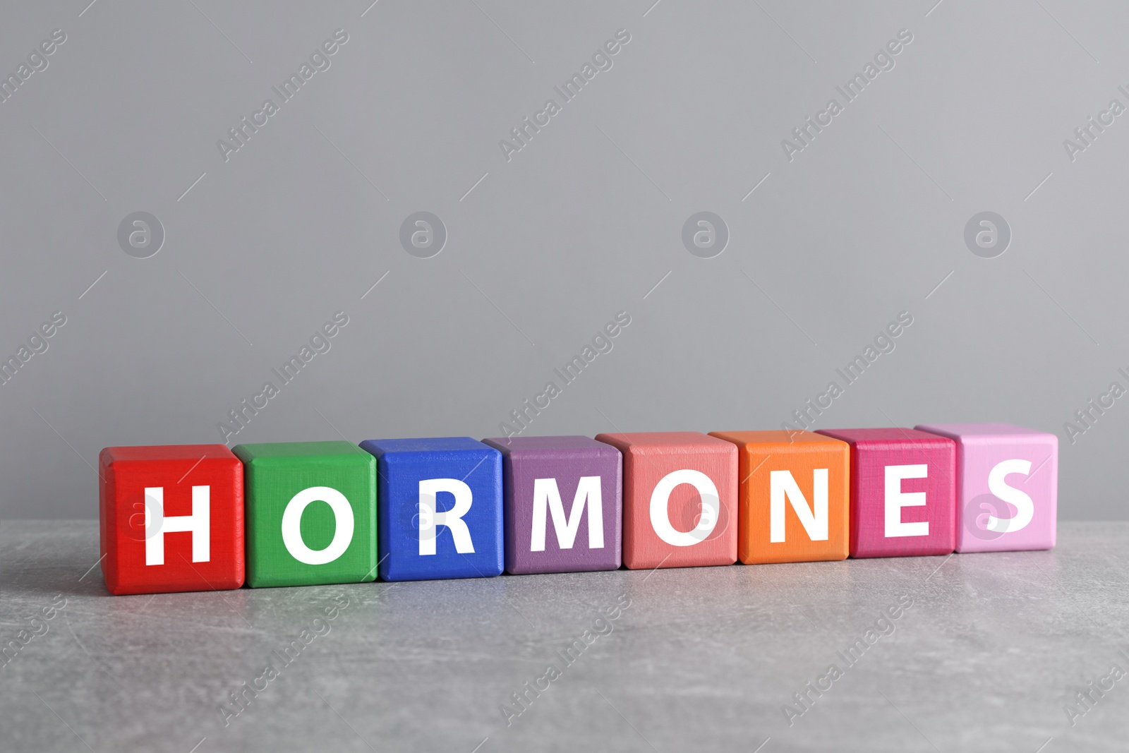 Photo of Word HORMONES made with colorful cubes on grey table