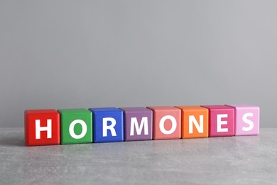 Photo of Word HORMONES made with colorful cubes on grey table