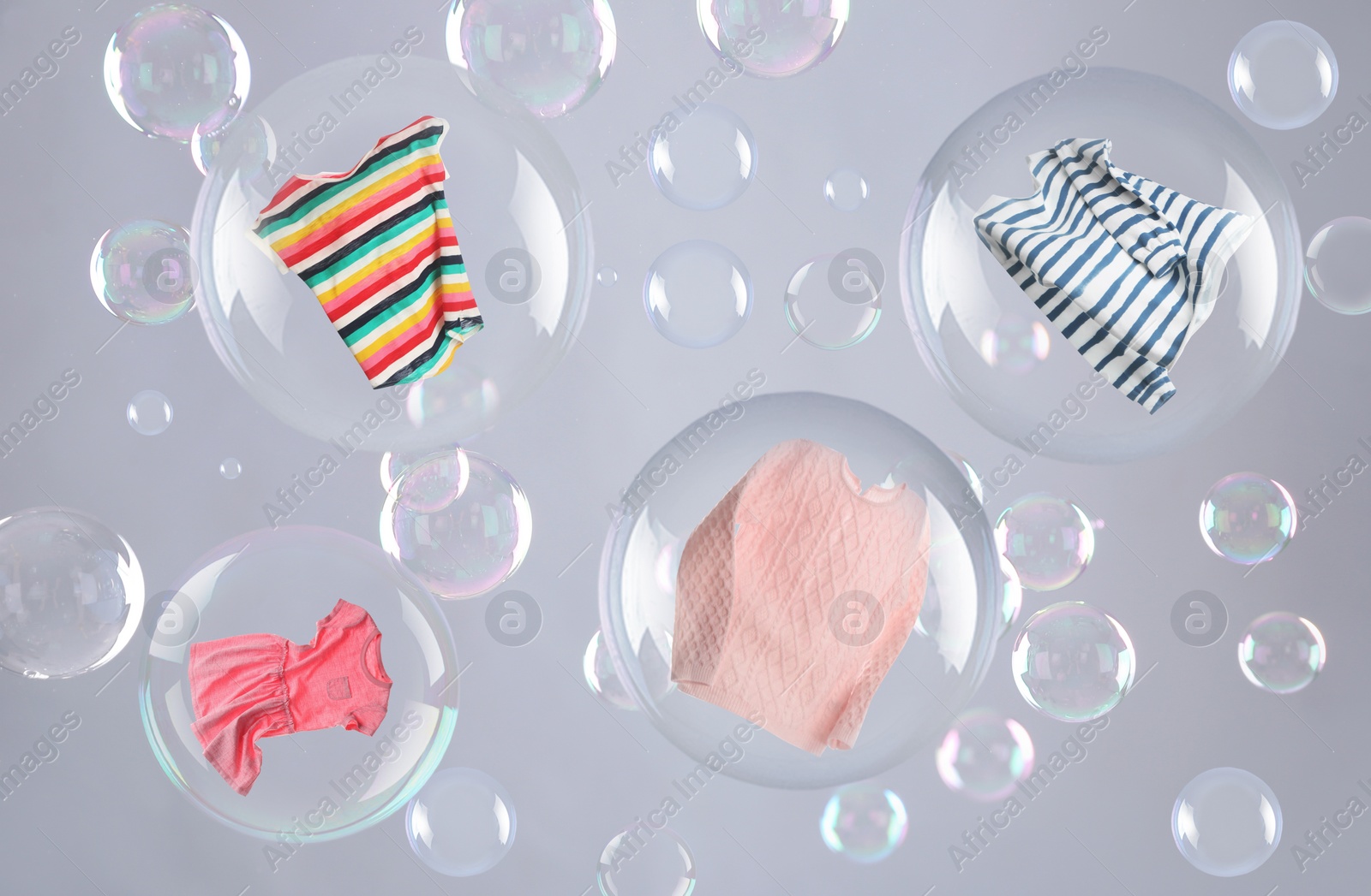 Image of Washing powder bubbles with clothes against grey background