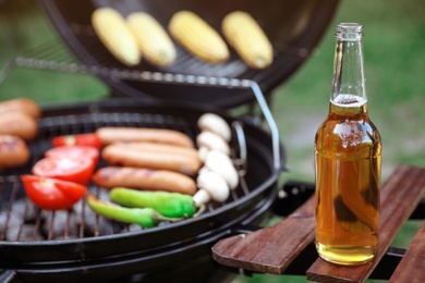 Photo of Bottle of beer on barbecue grill shelf outdoors