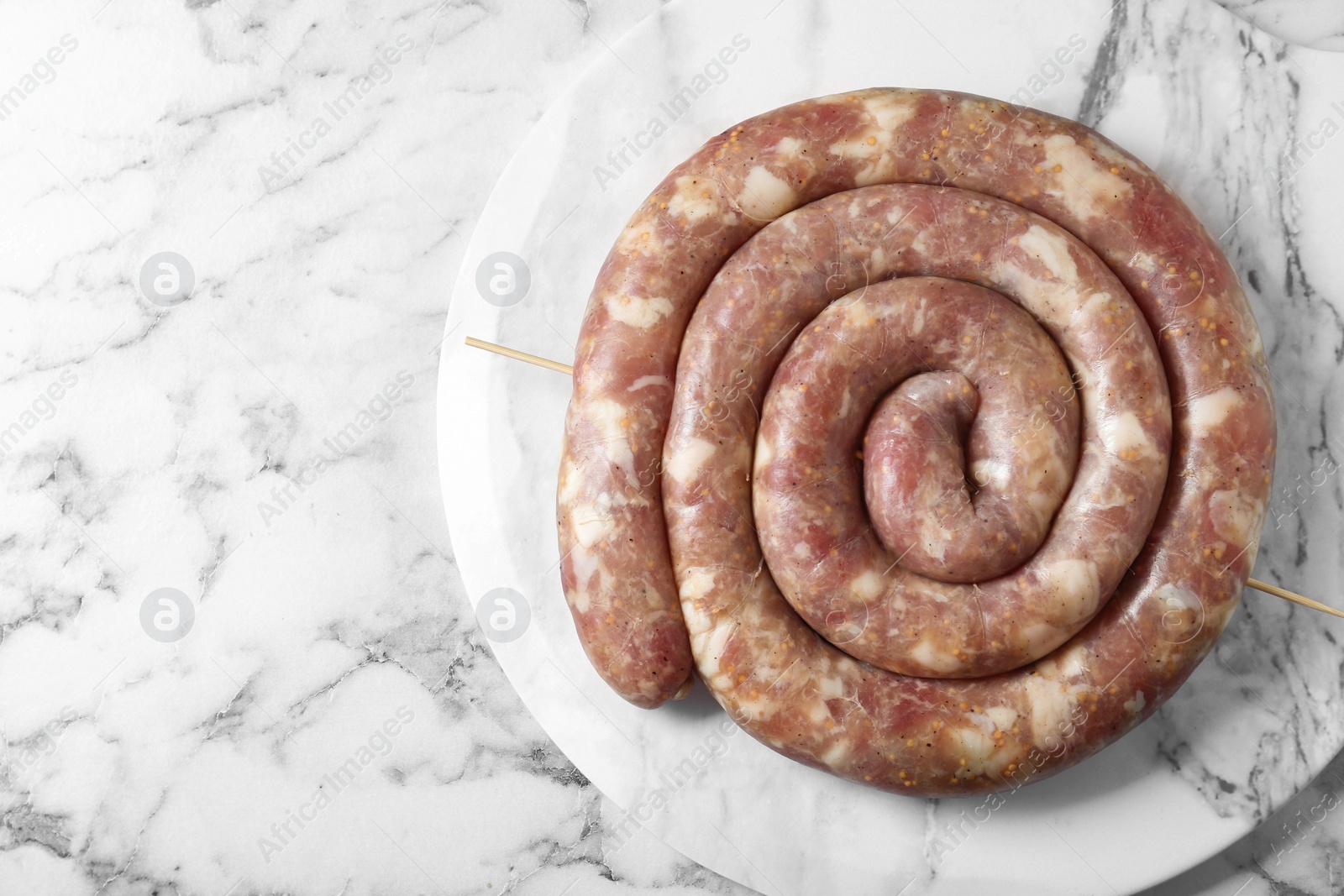 Photo of Raw homemade sausage on white marble table, top view. Space for text