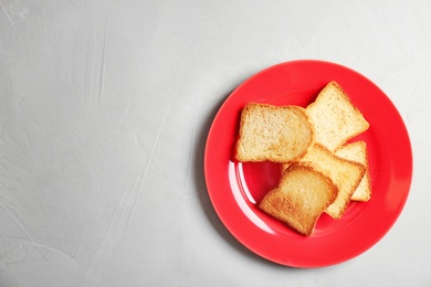 Plate with toasted bread on grey background, top view