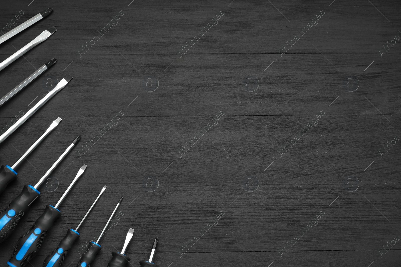 Photo of Set of screwdrivers on black wooden table, top view. Space for text