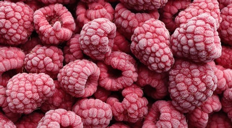 Tasty frozen raspberries as background, top view