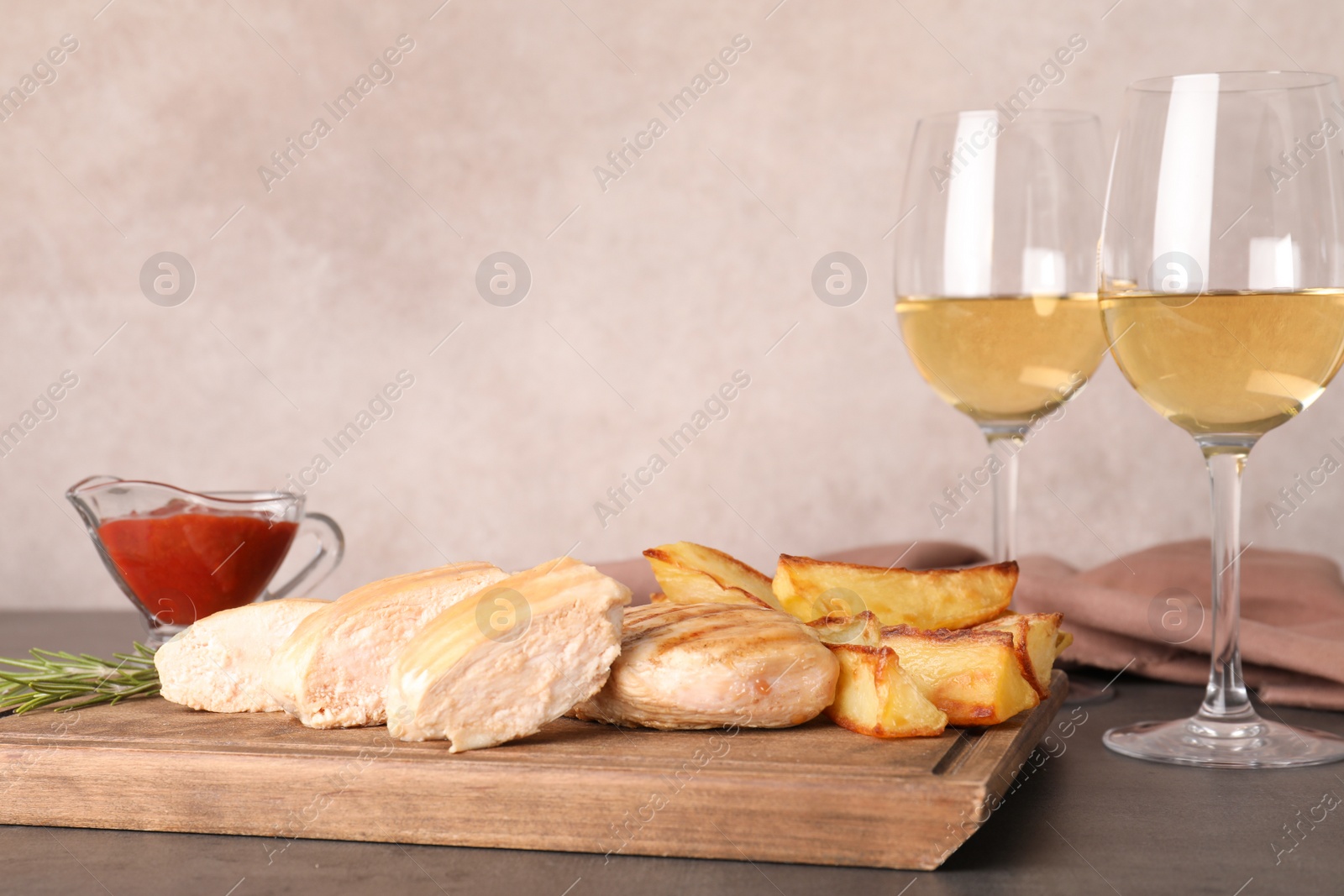 Photo of Grilled meat served with garnish, sauce and wine on table. Space for text