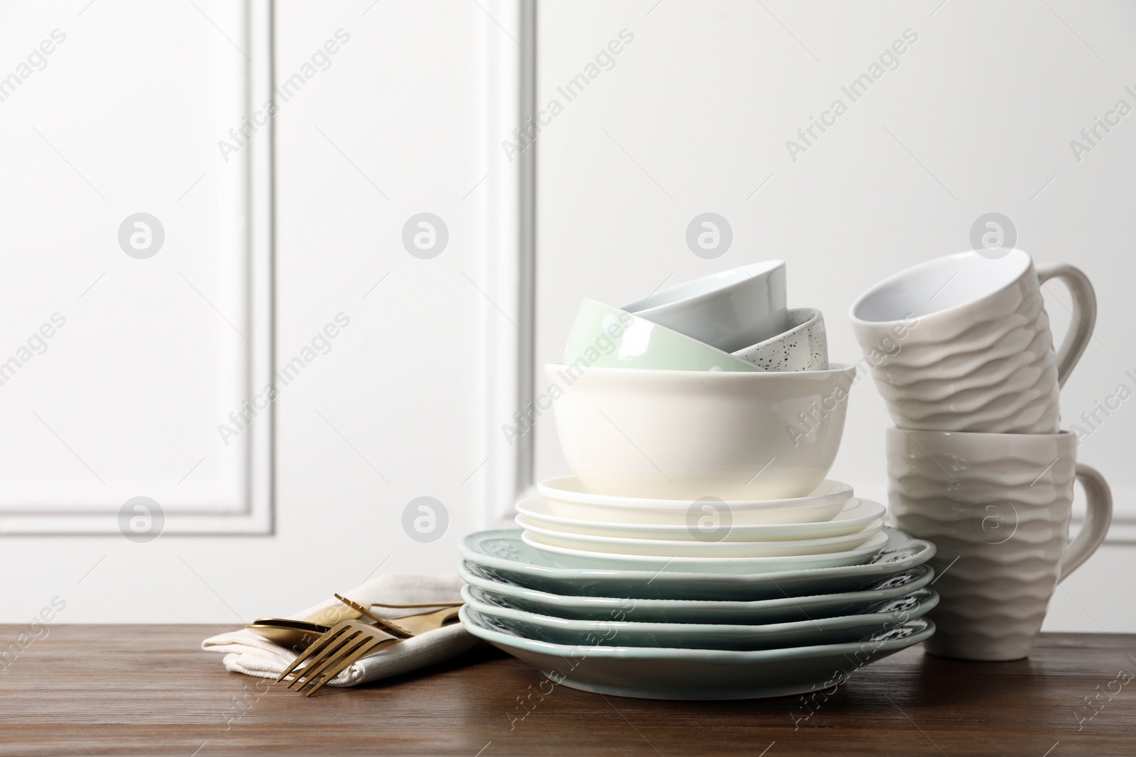 Photo of Beautiful ceramic dishware, cups and cutlery on wooden table, space for text