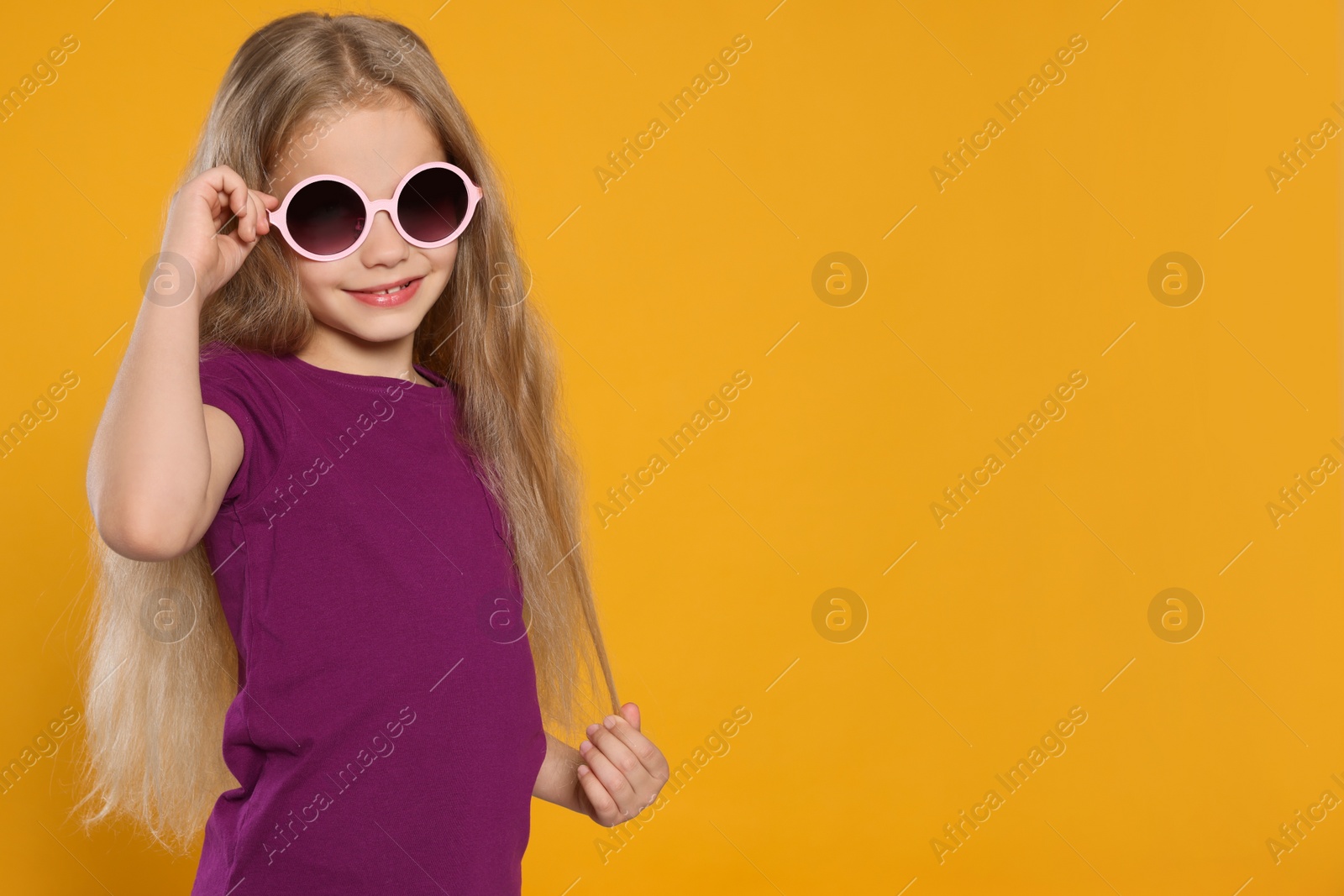 Photo of Girl wearing stylish sunglasses on orange background, space for text