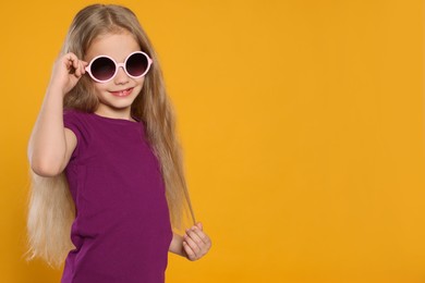 Photo of Girl wearing stylish sunglasses on orange background, space for text