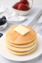 Photo of Delicious pancakes with butter and honey on white table, closeup