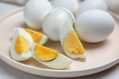Photo of Plate with hard boiled eggs on white wooden table, closeup