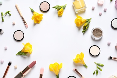 Different makeup products and flowers on white background, top view with space for text