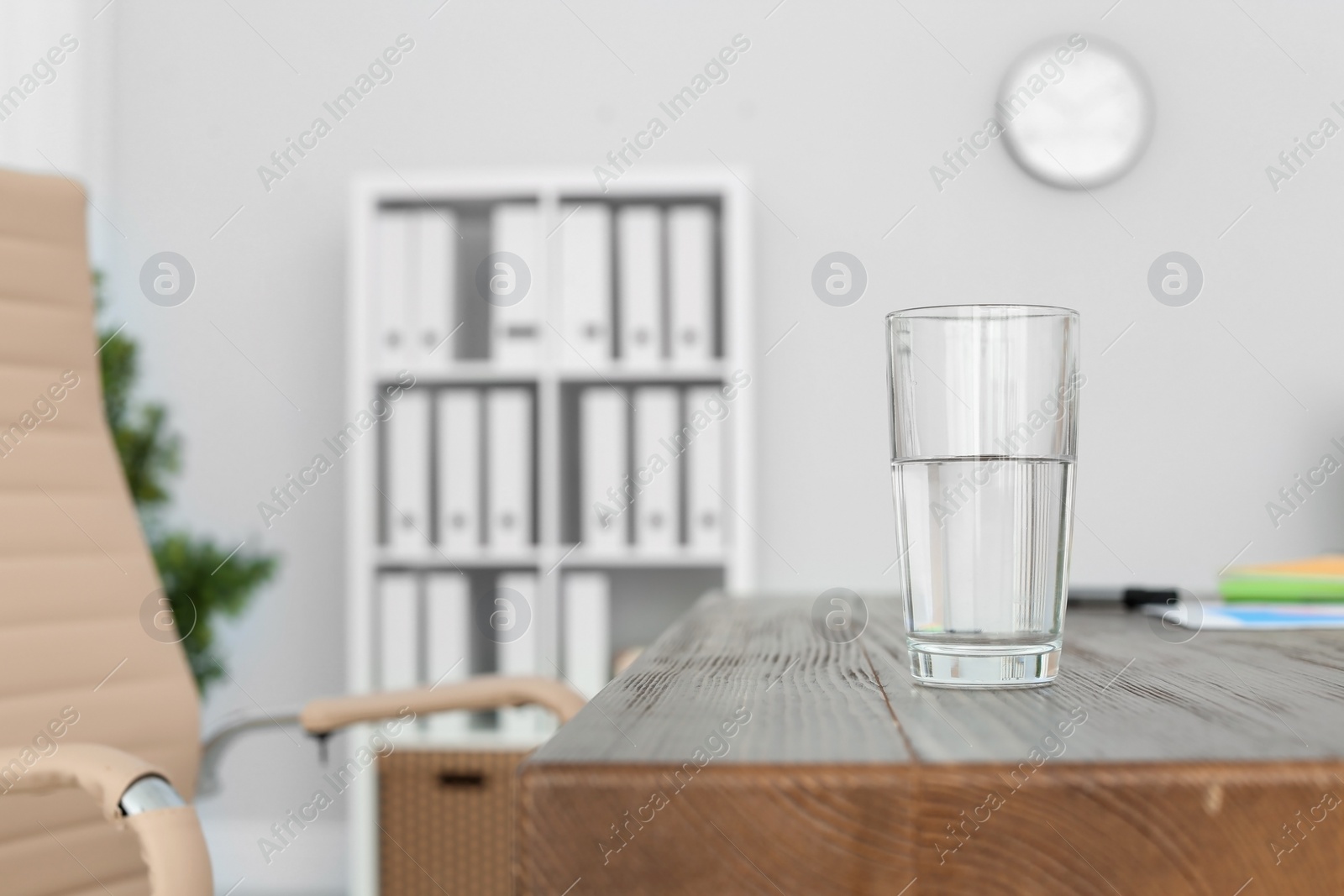 Photo of Glass of water on table in office. Space for text